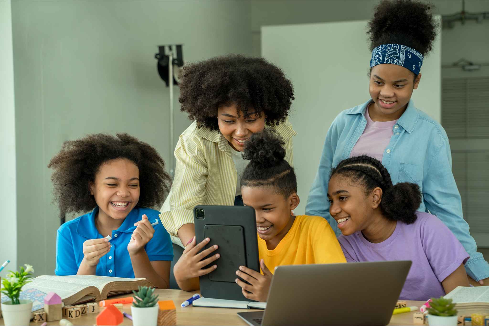 Picture of five (5) girls interacting with an iPad